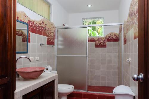 a bathroom with a shower and a sink and a toilet at Casa Cedro - Portasol Vacation Rentals in Matapalo