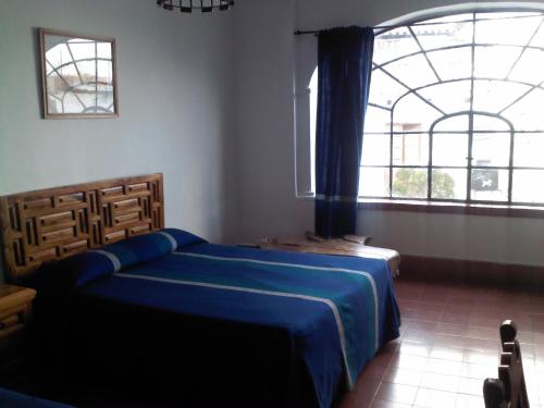 a bedroom with a blue bed and a large window at Hotel Santa Prisca in Taxco de Alarcón