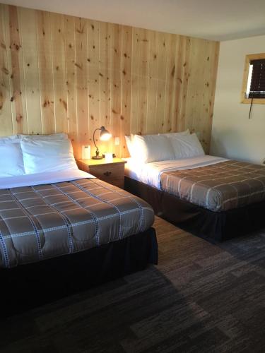 two beds in a room with wooden walls at Lull-Abi Inn in Egg Harbor
