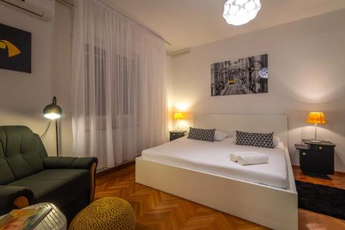 a bedroom with a white bed and a green chair at Apartman Karmen in Trogir