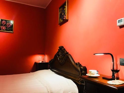 ein rotes Schlafzimmer mit einem Bett und einem Schreibtisch mit einer Lampe in der Unterkunft Gemma Apartments Milano Rho Fiera Apt2 in Lainate