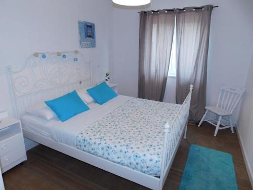 a bedroom with a white bed with blue pillows and a chair at Apartman Karmen in Tučepi
