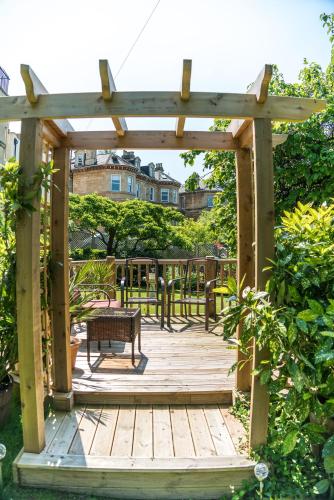 a wooden pergola with a bench on a deck at Oldfields House in Bath
