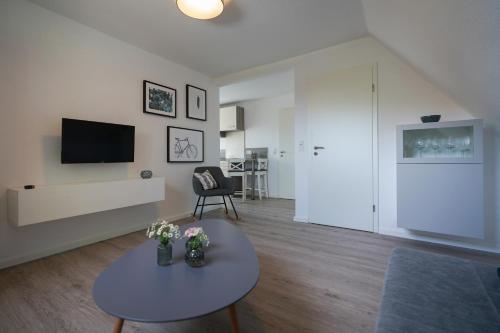 a living room with a table and a tv at Dünenhus Borkum in Borkum