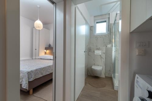 a small bathroom with a bed and a toilet at Apartments Flora Trogir in Trogir
