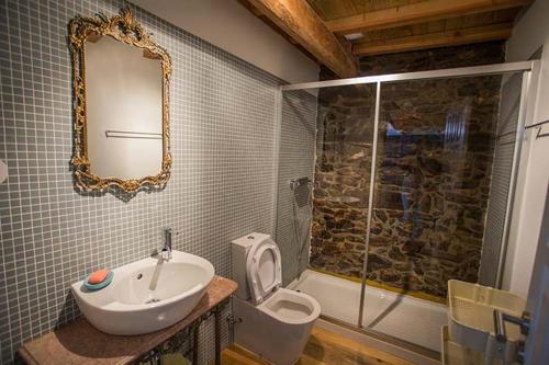 a bathroom with a sink and a toilet and a mirror at Casa da Assudra in Vila Verde