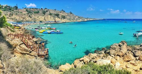 a beach with boats and people in the water at PMP Adamia Apartments in Peyia