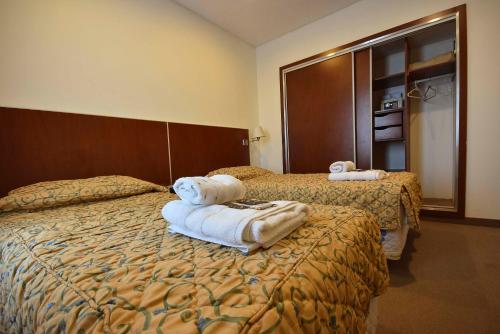 a hotel room with two beds with towels on them at Hotel Playa in Comodoro Rivadavia
