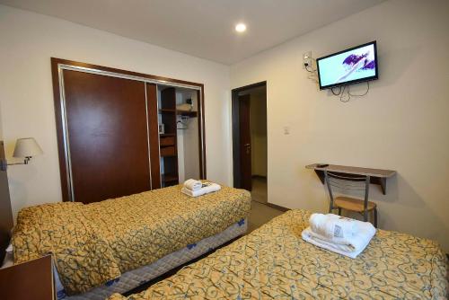 a hotel room with two beds and a flat screen tv at Hotel Playa in Comodoro Rivadavia