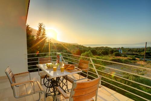 a table and chairs on a balcony with the sunset at Ideales Resort in Trapezaki