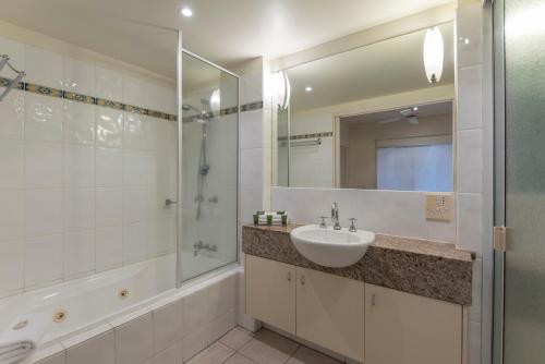 a bathroom with a sink and a shower and a mirror at Mowbray By The Sea in Port Douglas