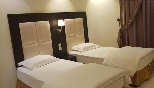 two beds in a hotel room with white sheets at روح الأصيلة للشقق المخدومة Roh Alaseilah Serviced Apartments in Taif