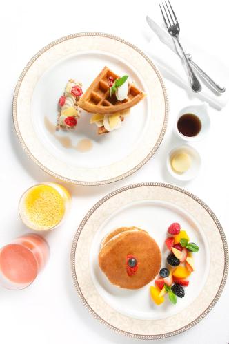 Zwei Teller mit Waffeln und Obst standen auf einem Tisch. in der Unterkunft Shangri-La Apartments in Singapur