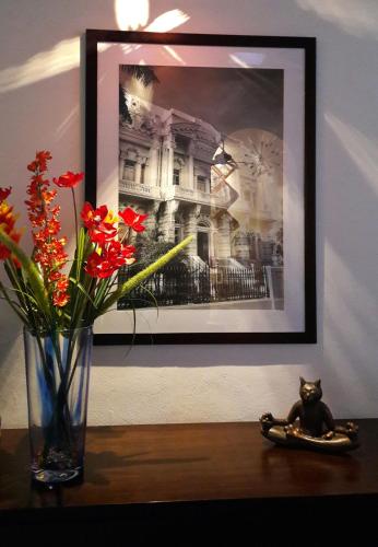 a vase with flowers on a table with a picture at Merida Santiago Hotel Boutique in Mérida