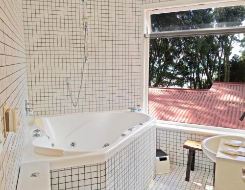 a white bath tub in a bathroom with a window at Ohiwa Seascape Studios in Opotiki