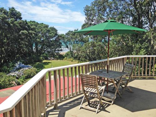 a table and chairs with an umbrella on a balcony at Ohiwa Seascape Studios in Opotiki
