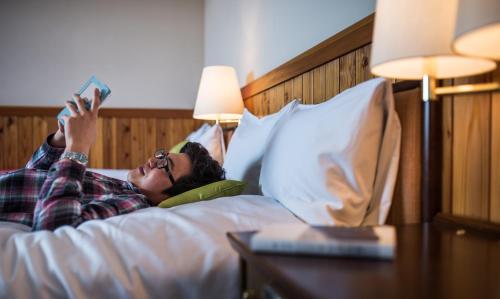 a woman laying in bed reading a book at Okushiga Kogen Hotel in Yamanouchi