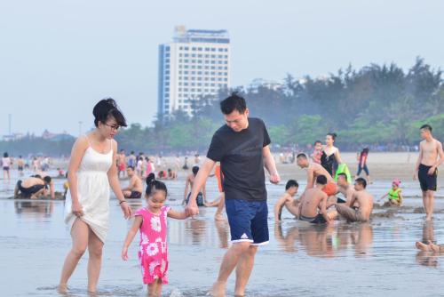 a family walking in the water at the beach at Thanh Tu Hotel in Cửa Lò