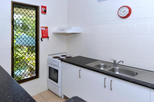 uma cozinha com um lavatório e um relógio na parede em City Gardens Apartments em Darwin