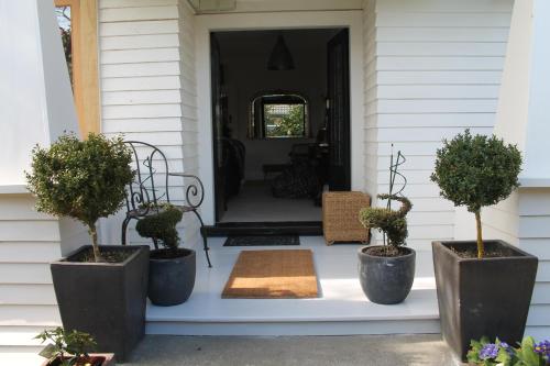 a front porch with three potted trees in pots at Beautiful Bungalow CBD in Blenheim