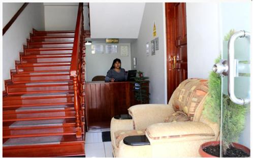 una mujer sentada en un escritorio en una habitación con escaleras en Hostal Residencial Lino, en Huaraz