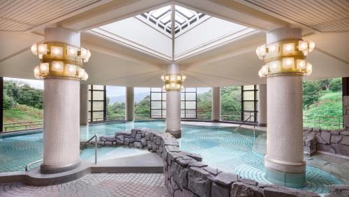 a large indoor swimming pool with columns and a rock wall at Izu Marriott Hotel Shuzenji in Izu