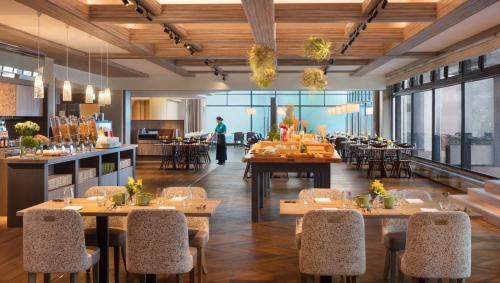 a restaurant with tables and chairs and a person in the background at Izu Marriott Hotel Shuzenji in Izu