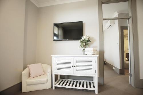 a living room with a white cabinet and a chair at Hotel Bondi in Sydney