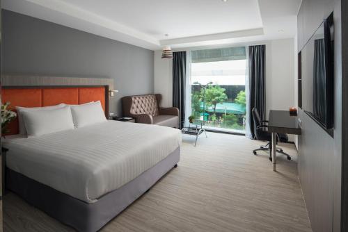 a bedroom with a bed and a desk and a television at Grand 5 Hotel & Plaza Sukhumvit Bangkok in Bangkok