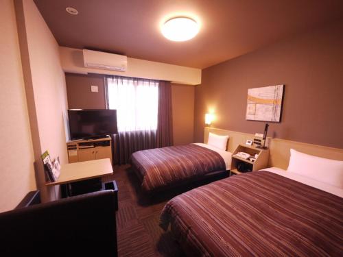 a hotel room with two beds and a television at Route Inn Grantia Komatsu Airport in Komatsu