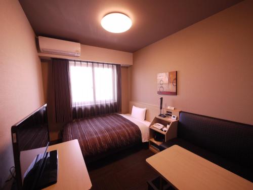 a hotel room with a bed and a window at Route Inn Grantia Komatsu Airport in Komatsu