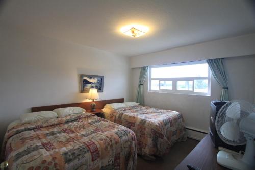 pokój hotelowy z 2 łóżkami i oknem w obiekcie Sunset Motel w mieście Port Alberni