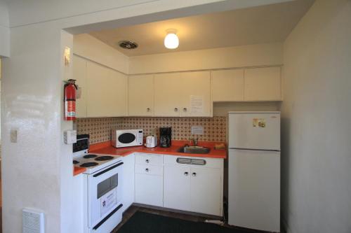 a kitchen with white cabinets and a white refrigerator at Sunset Motel in Port Alberni