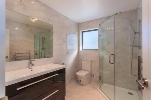 a bathroom with a shower and a sink and a toilet at Stunning Stay In Glen Eden Auckland in Auckland