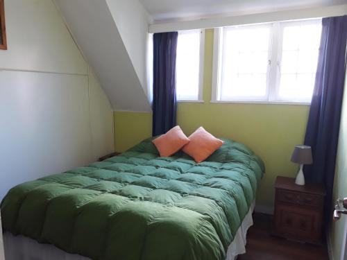 a bedroom with a green bed with two pillows at Casa Oriente Viña in Viña del Mar