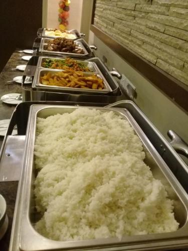 a buffet line with dishes of rice and other food at Dreamtel Jakarta in Jakarta