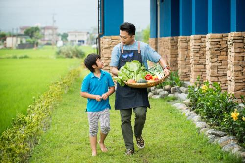 a man holding a basket of vegetables with a boy at Fly Inn 飛旅宿 in Dongshan