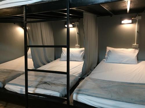 two bunk beds in a room with white beds at Beehive Phuket Old Town Hostel in Phuket Town