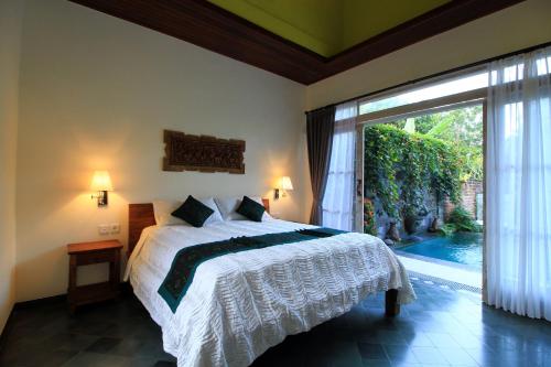 a bedroom with a bed and a large window at Villa Ketut Kartika in Ubud