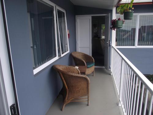 two wicker chairs sitting on the front porch of a house at Avenue Heights Motel in Whangarei