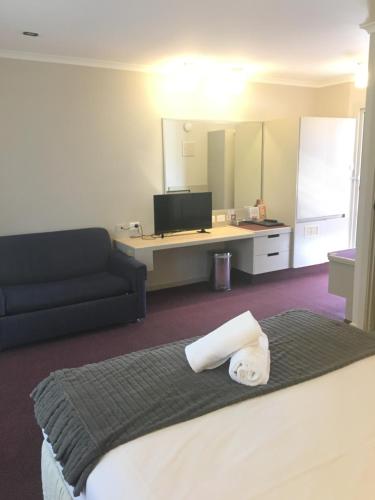 a hotel room with a bed and a couch and a television at Ringwood Lake Inn in Ringwood