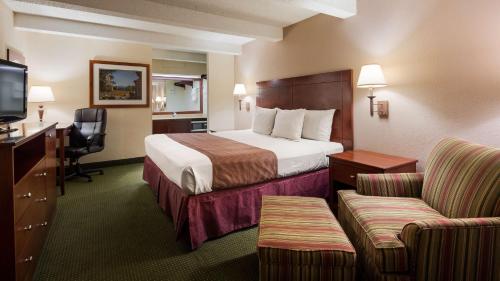 a hotel room with a bed and a chair and a television at Best Western Montis Inn in Saint Robert