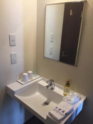 a bathroom with a white sink and a mirror at Ofunato Onsen in Ōfunato