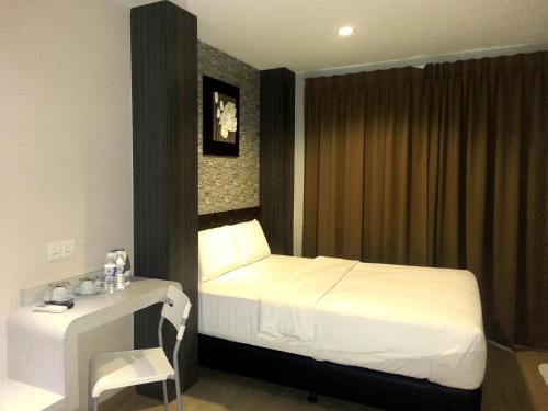 a bedroom with a bed and a table and a chair at Alor Boutique Hotel Sdn Bhd in Kuala Lumpur