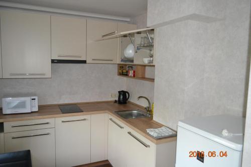 a small kitchen with white cabinets and a sink at Melīna in Rēzekne