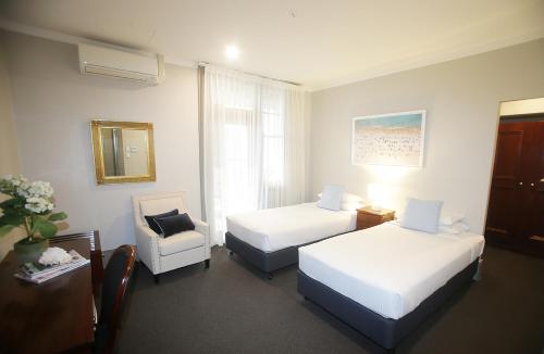a hotel room with two beds and a chair at Hotel Bondi in Sydney