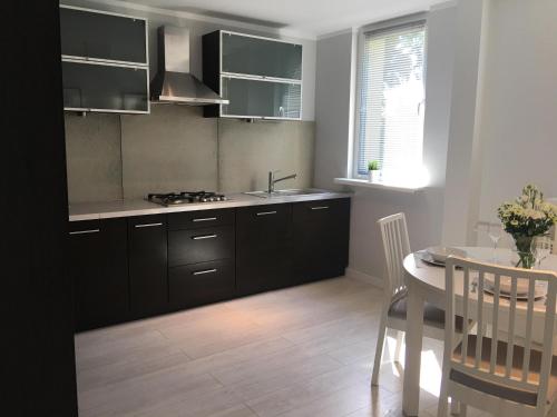 una cucina con armadi neri, un tavolo e una sala da pranzo di Mg Apartamenty - Apartament 51 a Oświęcim