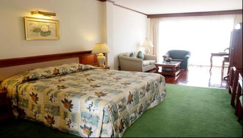 ein Schlafzimmer mit einem Bett und einem Stuhl in einem Zimmer in der Unterkunft Purimas Beach Hotel & Spa in Ban Chang