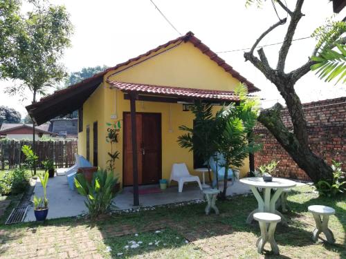 a small yellow house with a table and chairs at Coco Country Homes in Melaka