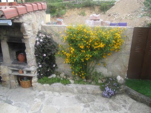 a stone wall with some flowers on it at Holiday Home La Asomailla in Hoyos del Espino